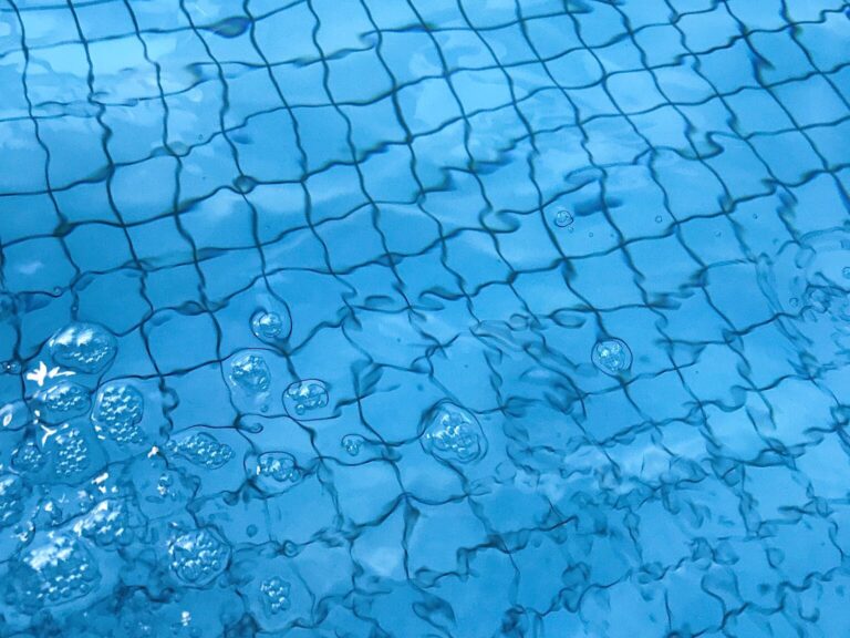From above of transparent clean water of swimming pool with ceramic bottom in daylight
